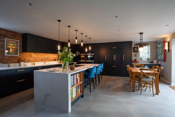 Spacious kitchen with a large island, black cabinetry, and a dining area with wooden furniture.